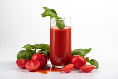 Bardakta domates suyu. Beyaz arka planda domatesler var.