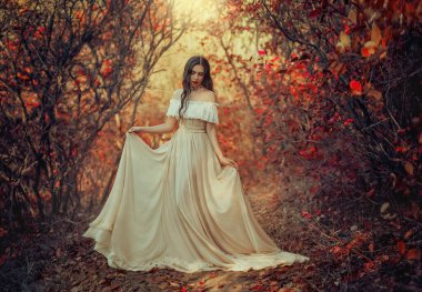 Art photo fantasy woman queen standing in gothic autumn forest, white vintage style dress. Girl princess beauty face long wavy hair elegant sexy bare open shoulders. Red orange yellow color dark tree