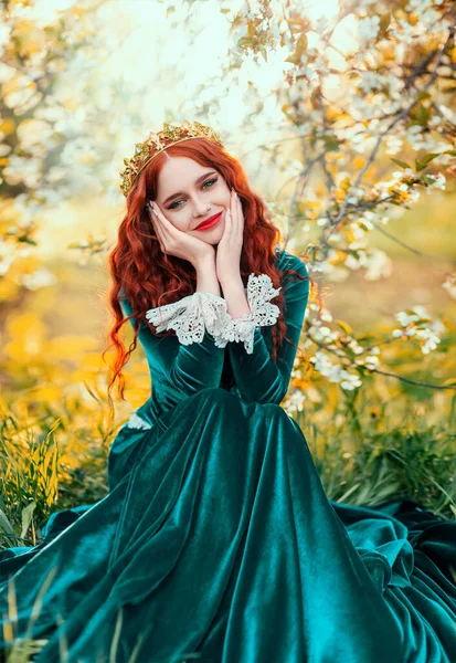 草の上に座って黄金の王冠のファンタジー肖像幸せな赤毛の女性の女王 女の子プリンセス笑顔顔緑ヴィンテージスタイルのドレス 赤い唇薄い肌の長い髪 春の自然木の太陽光写真 — ストック写真
