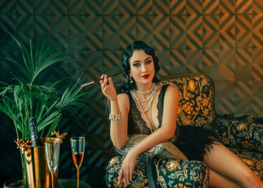 1920 'lerin stili Mutlu seksi kanepede oturan, kısa siyah elbiseli devekuşu tüyü. Kız elinde ağızlık tutuyor. Altın klasik lüks iç mekan. Beyaz inci boncuklar, soğuk dalgalı saç stili..