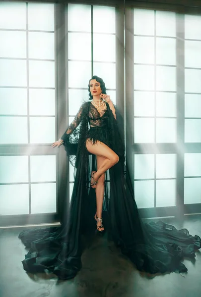 20世纪20年代复古风格的浪花女士 幻想性感女女王站在法国大窗户旁边 长腿模特摆出一副光溜溜的样子 旧式皇家黑色连衣裙 黑暗的皇家房间神奇的光 哥特式女孩 — 图库照片