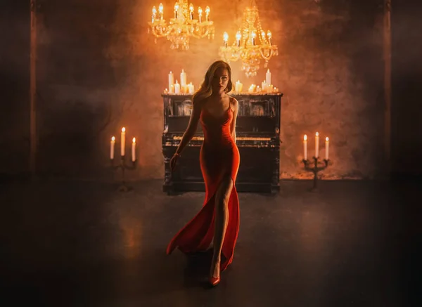 黑暗轮廓奇幻女士哥特式美女金发红裙走在豪华房间里 黑色钢琴蜡烛点着 长腿时装模特性感女吸血鬼女王的晚礼服 — 图库照片