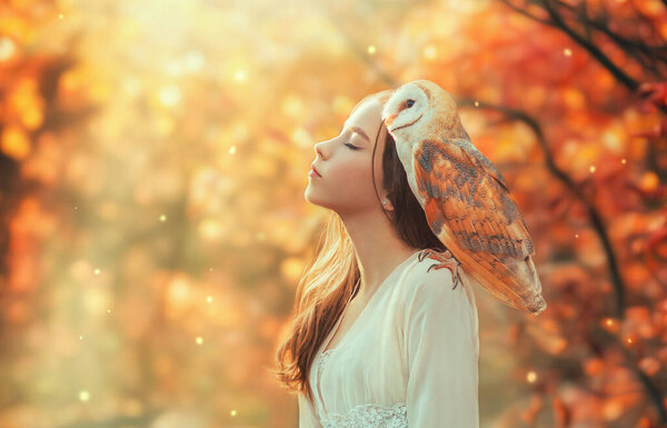 Fantasy girl princess teenager with white bird barn owl on shoulder. Eyes closed pretty face enjoying magical divine sun light. Bright colorful nature forest trees. vintage dress dream magic concept.