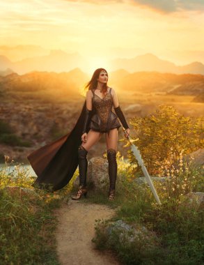 Fantezi kadın Viking Prenses savaşçı. Savaşçı kız Amazon. Leydi İskandinav tarzı seksi Valkyrie tanrıçası elinde kılıç tutuyor. Deri kostümlü zırh rüzgarda uçuşuyor. Dağlar gün batımı gökyüzü doğa yaz