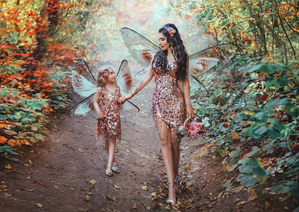 幻想的なピクシーの女の母親と幸せな娘の小さな妖精の女の子が一緒に秋の森の中を歩く コンセプト家族の愛の思いやり 蝶の翼の衣装創造的なピンクの光沢のあるドレス オレンジの木アート写真 — ストック写真
