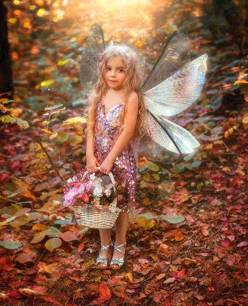 ポートレートファンタジーの小さな妖精の女の子 ピクシーの翼創造的な衣装は手に花束のバスケットを保持しています 子供の幸せな天使蝶笑顔 自己王女 魔法の光の秋の木 ピンクのドレス — ストック写真