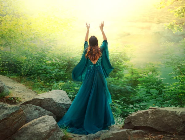 幻想的な女性の女王は 夏の森の手で神の魔法の太陽の光の空に上げ祈る 風の中で飛んで長い絹の緑のドレス生地の少女 謎の女神バック人生の調和を楽しんでリアビュー — ストック写真