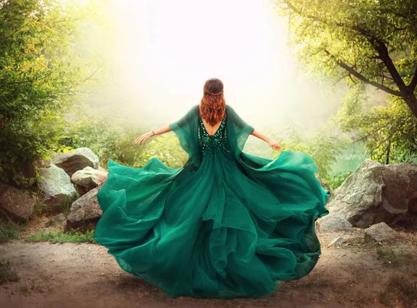 Fantasy happy woman redhead queen runs in magical forest nature. Girl in long elegant royal vintage green dress. silk fabric skirt flying fluttering in wind. Art photo open sexy back, without face.