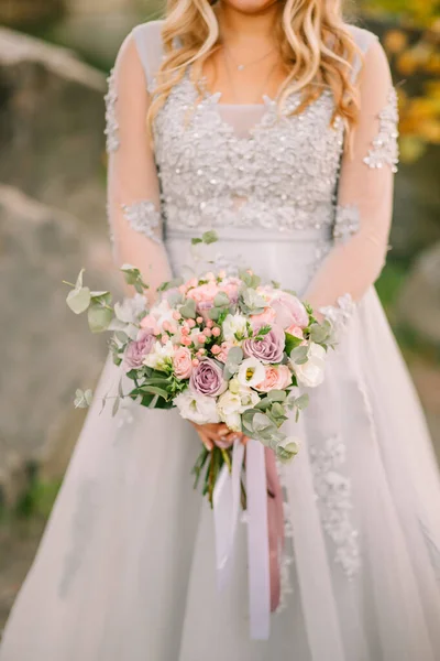 快乐的新娘特写女性手牵着婚礼创意花束白色紫色玫瑰浆果桉树植物新娘白色灰色连衣裙 金发女郎秋天的自然森林绿树 — 图库照片
