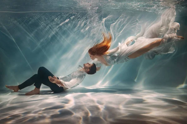 恋爱中的快乐夫妻在水下畅游 女神像缪斯激励着男作家诗人创作者 少女在海底救溺水的家伙 红头发白色长丝连衣裙飘扬 艺术照片 — 图库照片