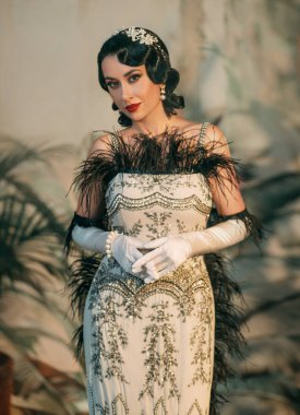 Sexy fantasy flapper woman in 20s old style silver retro lady evening dress black feather boa curls hairstyle pearl long gloves. Vintage girl art photo Roar 1920s fashion model red lips holiday makeup clipart