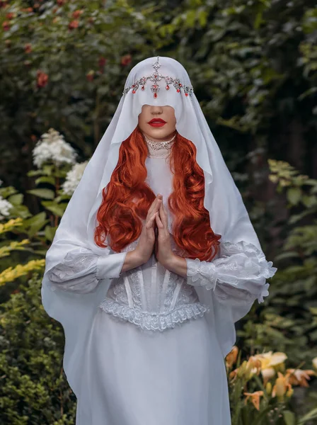 穿着白色复古服装的幻想女人圣洁的处女膜被丝绸面纱遮掩着 红头发女修女皇后 中世纪的公主新娘在花园里种着绿树花 神秘的形象性感的女吸血鬼 — 图库照片