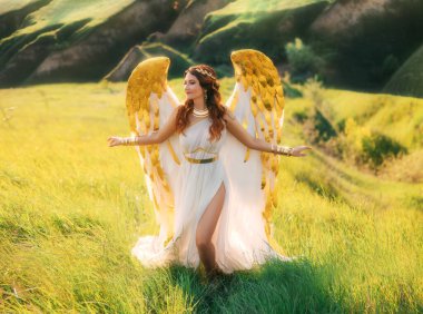 Sanat fotoğraflı fantezi kadın melek, altın kuş kanatlarıyla yazın doğa perisi kız Yunan tanrıçası uzun beyaz antika elbise yaratıcı mücevherler. Yeşil çim tepeleri ilahi güneş ışığı.