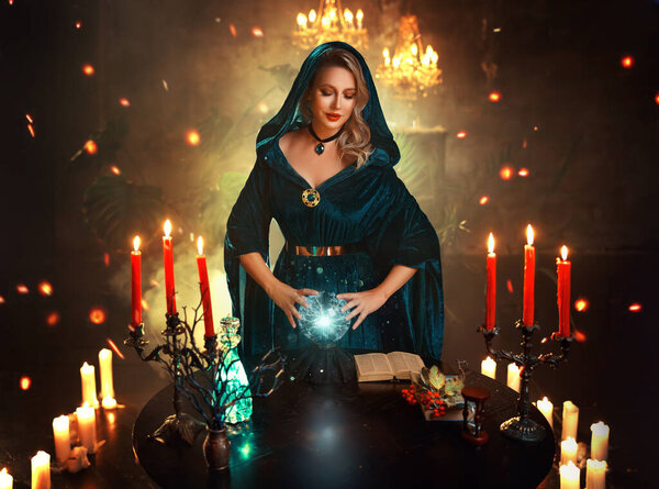 Фантазия счастливая улыбающаяся женщина ведьма создает волшебную, темную готическую комнату полный дым сверкает свечи горящие, сексуальная девушка волшебница колдунья гадалка держа волшебный хрустальный шар. Костюм леди Хэллоуин.