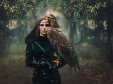Sanat portresi gerçek insanların fantezi kadını elinde beyaz kuyruklu vahşi kuş tutuyor. Elf savaşçısı güzel yüzlü, ormanda yürüyen kahverengi kuşlu kız. Kraliçe Avcı Siyah Başlık Siyah Ağaçlar Sis