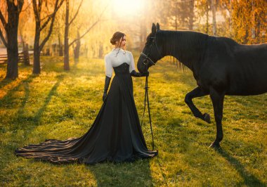 Fantezi kadın atını dizginler. Mutlu yetişkin kız güzel, asil bayan. Sevgi dolu hayvan evcil. Yaz doğa ormanı kutsal güneş ışığı. Uzun ipek siyah elbise, eski tarz. resim gerçek kişi.