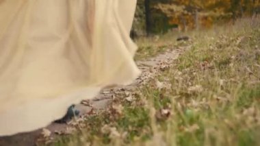 Ortaçağ elbisesi içinde neşeli, genç bir kadın ormanda koşuyor, doğanın tadını çıkarıyor. Ağır çekim. Kahverengi bej renkli eski elbise. Uzun kızıl saçlar rüzgarda uçuşuyor. Neşeli kız arka arkaya.