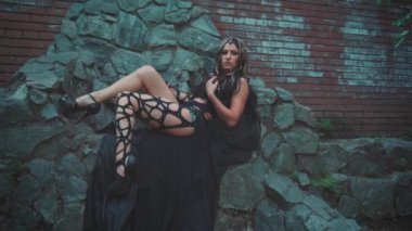 Gürültülü video. Fantezi kadın Medusa gorgon Yunan tanrıçası. Siyah gotik karnaval kostümü. Taş tahtta oturan manken kız. Baş altın yılanı saçı, korkunç makyaj. Kara Kraliçe