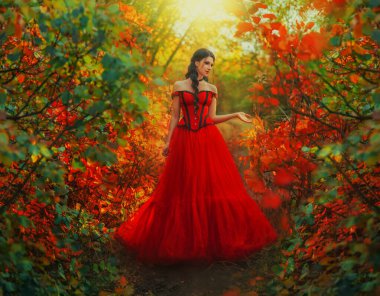 Sanat fotoğrafı gerçek gotik kadın prenses orman ağacında uzun siyah saçlı kırmızı elbiseyle yürüyor. Fantezi seksi kız prenses. Güneş ışığı doğa ağaçları yeşil kırmızı turuncu yapraklar. Kırmızı ağaç yapraklarına dokunan kadın..