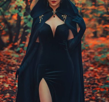 Gerçek sanat fotoğrafçısı. Sonbahar orman ağacında yürüyen bir kadın, Gotik siyah karnaval gece elbisesi başlıklı kırmızı dudaklı bir pelerin. Eski tarz uzun eldivenler. Fantezi kızı baloya gider, tatil etkinliğine..