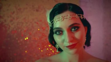 Portre seksi flapper kadın eski tarz parlak saç bandı ile 20 'li yaşlarda zarif bir bayanı canlandırıyor. Gülümseyen mutlu yüz bayramı makyajı dumanlı gözler kırmızı kahverengi dudaklar. Gece kulübü temalı şenlik odası.