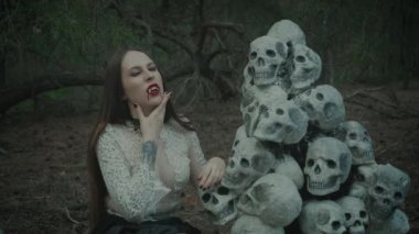 Seksi vampir kadının sahte dişleriyle yaladığı fantezi korku portresi. Kırmızı dudaklarda akan kan damlaları güzel ağız aç, tehlikeli yüz. Sanat cadılar bayramı makyajı Gotik kadın, poz veren kız