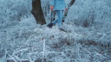 Bacaklar, kot pantolonlar, siyah ayakkabılar, kadın kış parkında yürüyor. Sıradan, kalın giysiler. Arkaplan ağaçları kar beyazı soğuk bir gün. Mutlu insan kış doğasının tadını çıkarır. Yaşam tarzı konsepti. Adım.