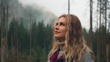 Gürültülü video. Genç mutlu kadın turist Polonya Karpatya dağlarında Zakopane 'de yürüyor. Çam ağacı. Yürüyüşçü kız, yağmurun damlaları altında, ıslak cilt gözleri kapalı gökyüzüne kaldırır. Doğanın tadını çıkar 