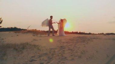 İki kişilik karanlık siluet romantik çift açıları gün batımında gökyüzü güneşinde buluşuyor. Aşıklar cennette evlenir. konsept aşk. Kostüm beyaz kanatlar. Fantezi elf kız melek ve erkek birlikte.