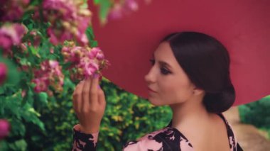 Eski film stili. Gürültü, film tahılları. Şirin bir kadın çiçek açan ağaçlara dokunur. Geniş kenarlı şapkalı çekici ve çekici bir kız. Doğa parfümü kokusu alıyorum. Geniş kenarlı şapkalı kız.
