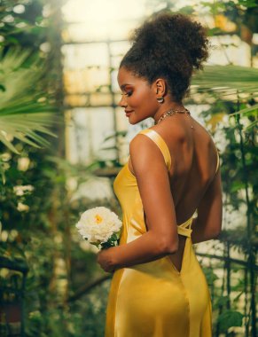 Gerçek sanat fotoğrafçısı. Fantezi kızı elinde taze beyaz şakayık çiçeği yeşil ağaç tropikal doğasını tutuyor. Mutlu Afro-Amerikan güzellik mankeni seksi kadın. Siyah kıvırcık saçlı. Sırtını aç.