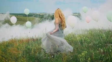 Genç mutlu sarışın kadın prenses yeşil doğada yürüyor, fırıl fırıl dönüyor, dans ediyor, etek çırpıyor, sallanan ipek mavisi gri elbise. Eski tarz ortaçağ yaz kıyafetleri. Dürüst kız gelin. Başında taç var.