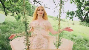 Genç mutlu kadın perisinin portresi. Uzun, sağlıklı, doğal sarışın. Sarışın bir kızın peri gibi güzel yüzü orman prensesi gibi. Nazik, utangaç gülümseme. Arkaplan Yazı Yeşil Ağaç Bahar Doğası