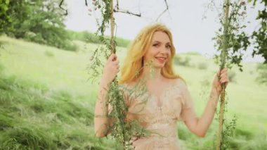 Mutlu güzel bir kadın. Doğal sarışın. Rüzgarda uçuşan uzun saçlı. Şirin, gülümseyen, samimi, sarışın, model, çayır ormanı elf prensesi gülümsemesi. Yaz doğası, bahar yeşili çimen ağacı.