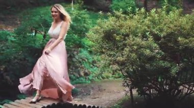 Dalgalı saçlı, uzun elbiseli, hareketli sarışın bir kadın. Beyaz dantelli bluz ve pembe ipek etek. Modern mutlu gelin. Georgia 'daki yeşil parkta keyifli bir yürüyüş..
