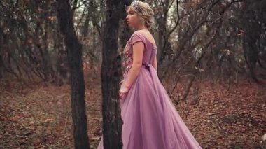 Güzel sarışın prenses mor, gür bir korse içinde duruyor. Korkmuş, ormanda kaybolmuş. Göz kamaştırıcı moda kraliçesi. Sonbahar arkaplanı, siyah ağaçlar portakal yaprakları. Sevimli genç yüz.