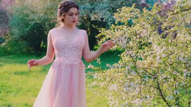 Mutlu gülümseyen kız modelleri, çiçek açan arka plan ağaçları rüzgarın üzerine düşen pembe beyaz çiçekler, bahar doğal yeşil çimenler. Zarif elbiseli kadın, sağlık konsepti alerjiden uzak.