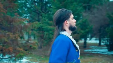 Muhteşem ortaçağ prensi, esmer adam, uzun saçlı, güzel biniciye gül çiçeği veriyor. Siyah atın üzerinde oturan mutlu, gülümseyen kadın. Klasik kırmızı elbise. Zarif mavi smokin. Kış doğa ormanı