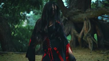 Sanat işlemini tersine çevirin. Fantezi portre kadın cadı ritüel dansı yapıyor. Seksi sihirbaz kız elini sıkar, uzun saç sineği ağır çekimde uçar. Siyah karnaval kostümü. Ağaç gece ormanı