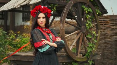 Ukraynalı mutlu kız kameraya bakar. Otantik kadın gülen surat. Ulusal etnik klasik kostüm siyah elbise şık vyshyvanka. Başında çelenk, başında kırmızı çiçek, gülünde haşhaş 4k.