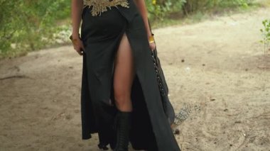 Demir zincirler tutan fantezi ortaçağ kadını zemin boyunca uzanıyor. Seksi cadı prenses vahşi ejderhayı karanlık ormanda yakalayıp evcilleştirmek istiyor. uzun siyah elbise. Kölelik esiri kavramı. 4k