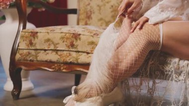 Seksi, kraliçe, kanepede oturan, elinde devekuşu tüyü tutan, bacakları okşayan güzel kadın vücudu. Fantezi Kız Prenses Viktorya dönemi tarzı lüks oda mumları yanıyor, klasik dantel dantel 4k