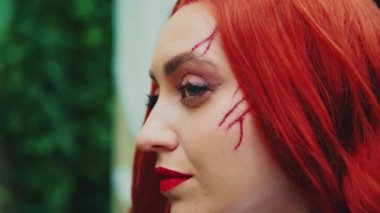 Fantezi sanat portresi. Kızıl saçlı kötü kadın. Cadılar bayramı makyajı. Klasik beyaz elbise. Yaz yeşili ağaçlar. Gotik kız model güzellik suratı. Kızıl saçlı seksi bayan.
