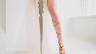 Yunan savaş tanrıçası Athena 'nın antik çelik kılıcı elinde tuttuğu fantezi portresi. Yaratıcı tasarım ipekten elbiseler yaratıcı elbise altın aksesuarlar klasik kostüm. Uzun saçlar rüzgarda uçuşuyor