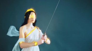 Yunan adalet tanrıçası fantezi portresi Themis 'i kör etti, savaş antik çelik kılıcı elinde tutuyordu. İpek beyaz elbise, altın aksesuarlar, klasik kostüm. Uzun saç kumaşı rüzgarda uçuşuyor.