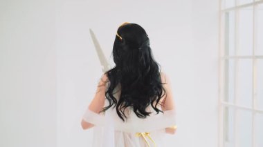 Yunan savaş tanrıçası Athena 'nın antik çelik kılıcı elinde tuttuğu fantezi portresi. Yaratıcı tasarım ipekten elbiseler yaratıcı elbise altın aksesuarlar klasik kostüm. Uzun saçlar rüzgarda uçuşuyor