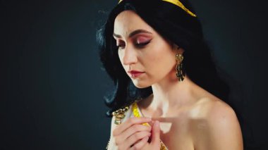 Fantezi sanat portresi parlak cilt güzelliği Yunan tanrıça kadın manken pozu verir. Afrodit kız seksi kraliçe. Beyaz elbiseli, altın kaplama, kumral, uzun saçlı, rüzgarda çırpınan sinek. Siyah stüdyo arka planı