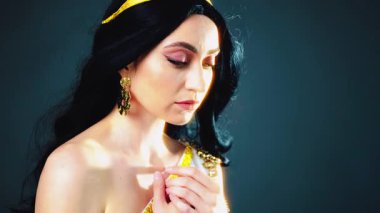 Fantezi sanat portresi parlak cilt güzelliği Yunan tanrıça kadın manken pozu verir. Afrodit kız seksi kraliçe. Beyaz elbiseli, altın kaplama, kumral, uzun saçlı, rüzgarda çırpınan sinek. Siyah stüdyo arka planı