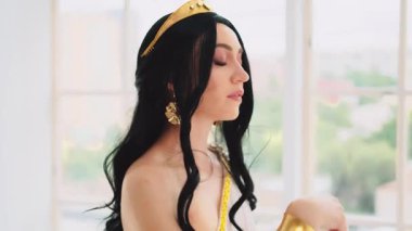 Fantezi kadın portresi kraliçesi, seksi gözler mükemmel cilt güzelliği saçlar rüzgarda uçuşuyor. Manken panoramik pencerenin yanında yürüyor, Peri Kız antika kraliyet tacına bakıyor.
