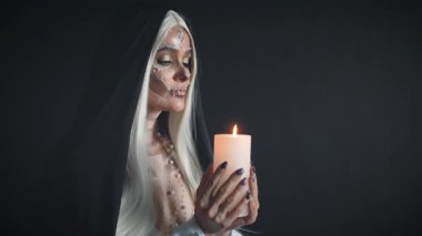 Ölü ruhların rahibesi yanan mum tutuyor ve ölü akrabalarıyla tanışmak için tören düzenliyor. Ölüm tanrıçası görüntüsü. Gizemli hayalet kameraya bakıyor ve diğer dünyayla bağlantı kuruyor..